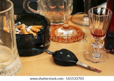 Car keys on the table full of empty glasses, bottles, full ashtray and spilled drink after a party, don\'t drink and drive concept