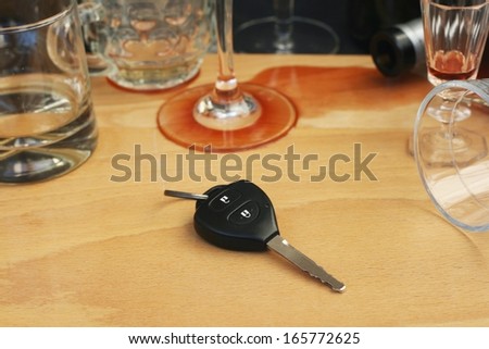 Car keys on the table full of empty glasses, bottles and spilled wine after a party, don\'t drink and drive concept