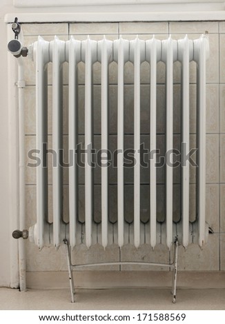 Old rusty heat radiator, retro tile in background