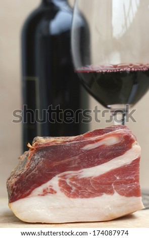 Typical Slovenian dry cured smoked ham called prsut from Slovenia with red wine in background