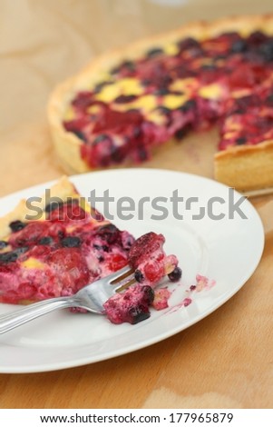 Piece of delicious raspberry, blueberry and blackberry sweet pie,a bite missing - eating a cake