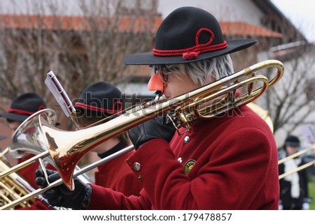 CERKNICA, SLOVENIA - MARCH 2, 2014: A man dressed as clown plays trumpet in a brass band at traditional Slovenian carnival called \