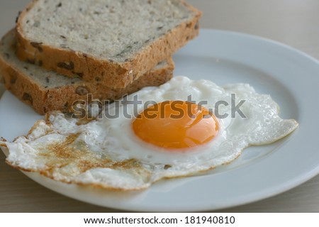 Organic sunny side up egg with whole wheat toast served on a plate on a kitchen table