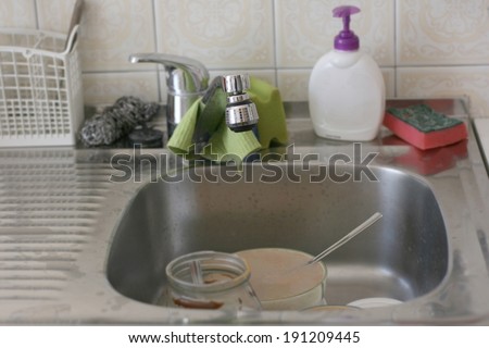 Dirty kitchen sink with different old cleaning sponges, focus on tip of faucet