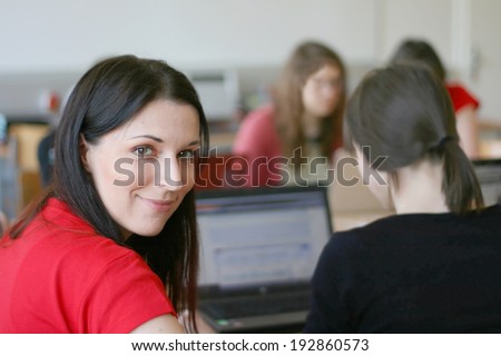 Woman on a laptop computer, working with a group of female university students of computer science, programming code