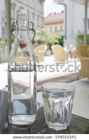 Drinking water is necessary on hot summer day, bottle of water and glass on table in italian style restaurant