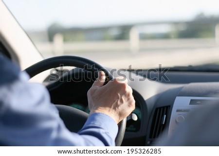 A businessman driving a car on highway, hands on the wheel