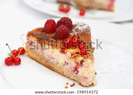 Piece of homemade cheese pie with berries, served with fresh redcurrant and raspberries