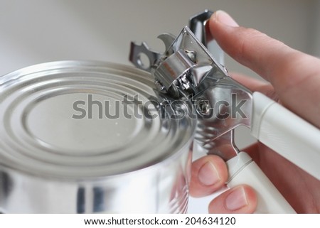 Tin opener opening a can in a kitchen