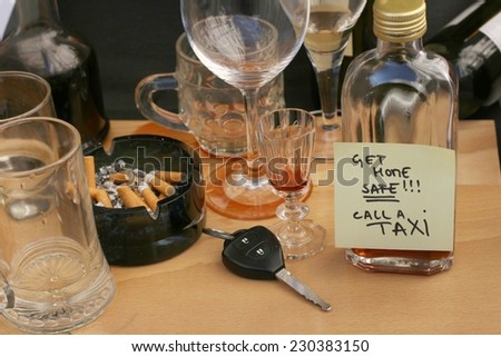 Car keys on the table full of empty glasses, bottles and ashtray at party, don\'t drink and drive concept, post it note for taxi