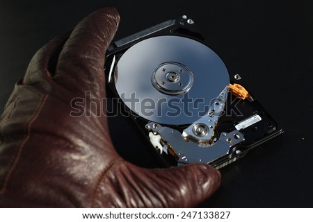 Protect your data, hand with glove over open hard disk drive, stealing information concept