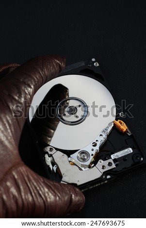 Protect your data, hand with glove over open hard disk drive, stealing information concept