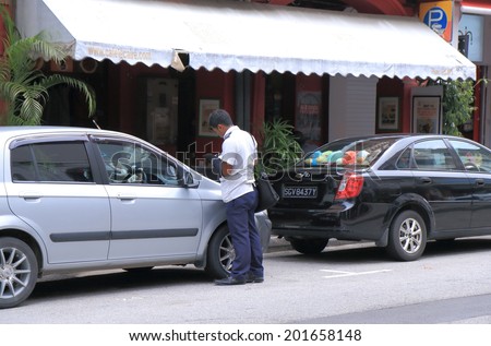 SINGAPORE - 27 May, 2014: Unidentified parking ticket inspector works in Arab Street. More than 90% of motorists pay parking fine promptly according to the URA Urban Redevelopment Authority.