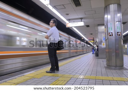 OSAKA JAPAN - 3 JUNE, 2014: Unidentified Japanese business man waits for subway at Osaka Subway station. Osaka Municipal Subway network has 13 million passengers daily.