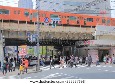 OSAKA JAPAN - APRIL 24, 2015: Unidentified people walk under train rail crossing bridge in Osaka. Osaka is the third largest city and an economic and entertainment hub of Kansai region.