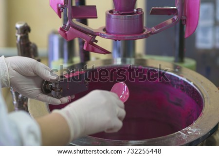 Manufacturing paint in a factory. Pink colored paint in an industrial environment.  A lady wearing rubber gloves while working with liquids