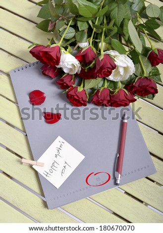 writing happy mother\'s dy on the notebook and some roses