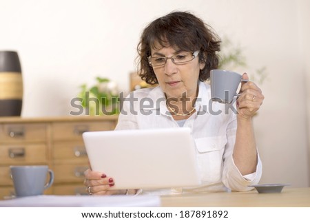 a middle-aged woman using a  computer tablet in her kitchen