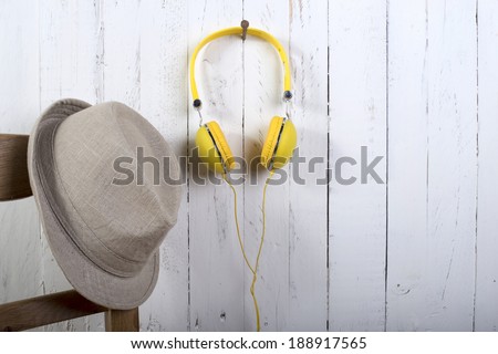 hat and yellow headphones hung on a wall painting white