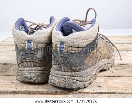 hiking shoes with mud laid on wood