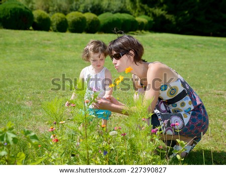 a beautiful mom is a hug to her daughter with a flower in his garden