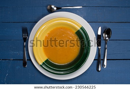 plate of pumpkin soup on a blue wooden table