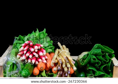 small crate with various seasonal vegetables on black background