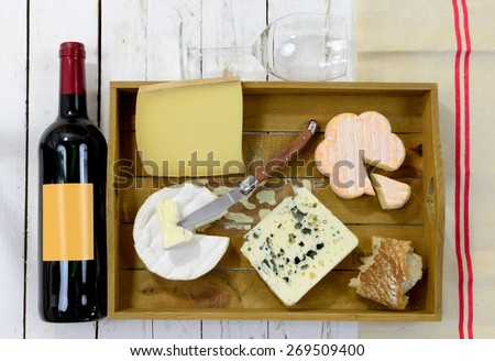 tray different french cheeses with bottle of red wine