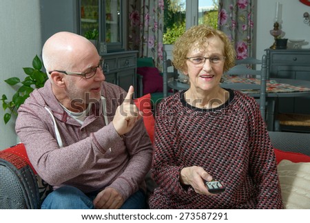 an elderly mother with her son watching tv in her house
