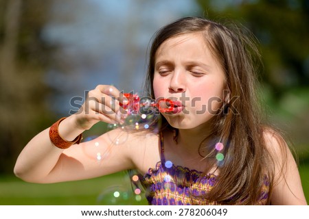 a little girl making soap bubbles in nature