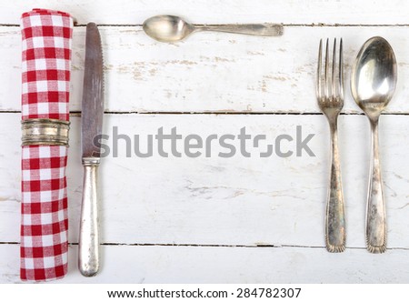 silver cutlery with red towel on an old white table