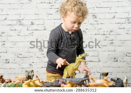 a little child plays with toys animals and dinosaurs