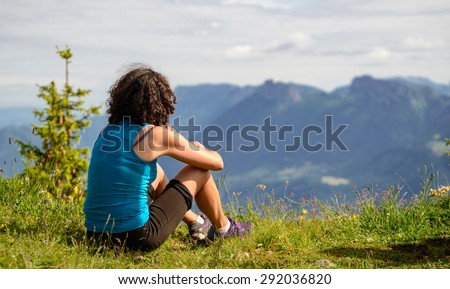 woman sitting on cliff and  looking at landscape
