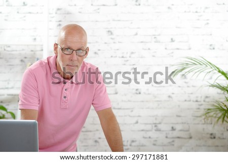 a businessman with a pink polo shirt works in his office