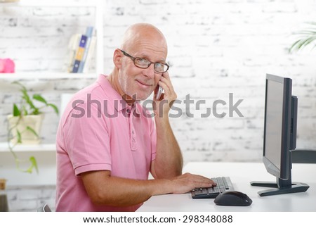 a businessman with a pink polo shirt at phone in his office