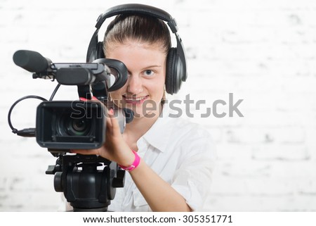 a pretty young woman with a professional  movie camera and headphones