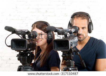 young man and woman with professional video cameras