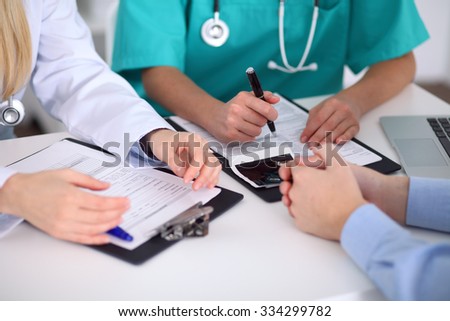 Doctors and patient are discussing something, just hands at the table