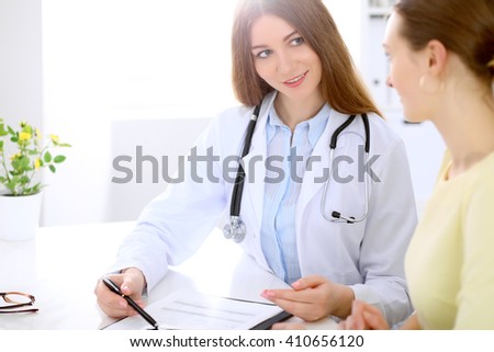 Doctor and  patient  sitting at the desk near window, sun shines