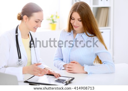 Doctor and  patient  sitting at the desk near window, sun shines
