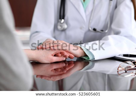 Friendly female doctor hands holding patient hand sitting at the desk for encouragement, empathy, cheering and support while medical examination. Bad news lessening, compassion