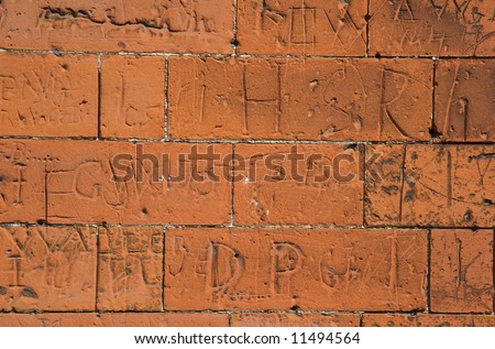 A red brick school wall covered with scratched eighteenth century graffiti for background or texture