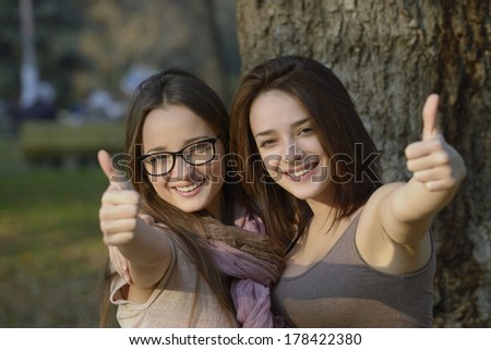 Two beautiful young women giving thumbs up sign and smiling