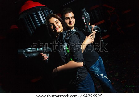 Dark room girl and funny guy playing laser tag