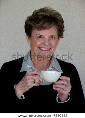 Attractive older woman drinking coffee or tea.