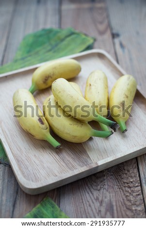 Golden bananas in the wooden plate with leaves