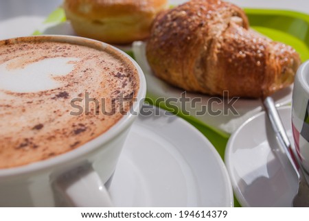 A tasty breakfast with coffee, cappuccino and croissant