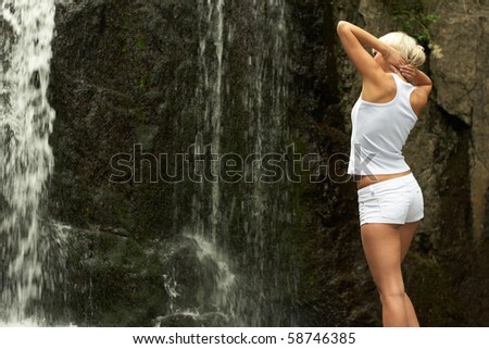Young sporting girl in shorts at the outdoor near to waterfall
