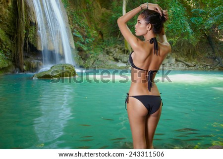 Female model in bikini in nature waterfall in Erawan, Thailand