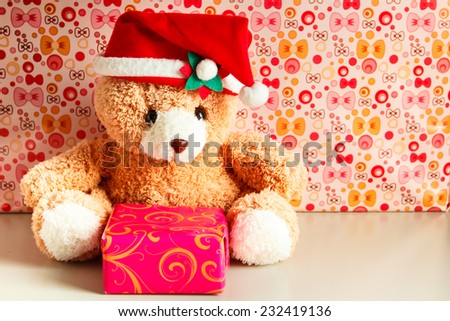 Teddy bear wearing a santa hat and gift.
